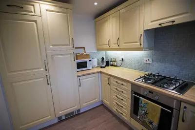 a kitchen with white cabinets and a stove top oven at Your home away from home in Bury Saint Edmunds