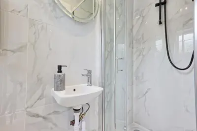 a white bathroom with a sink and a shower at 5 Bedroom Apartment - Weekly Deal - By Homestyles Hosts Short Lets and Serviced Accommodation Widford - Free Parking in Writtle