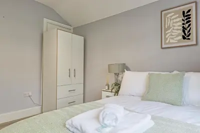 a bedroom with a white bed and a cabinet at 5 Bedroom Apartment - Weekly Deal - By Homestyles Hosts Short Lets and Serviced Accommodation Widford - Free Parking in Writtle