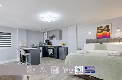 a bedroom with a large bed and a kitchen at Studio By Homestyles Hosts Short Lets & Serviced Accommodation Widford - Free WiFi in Writtle