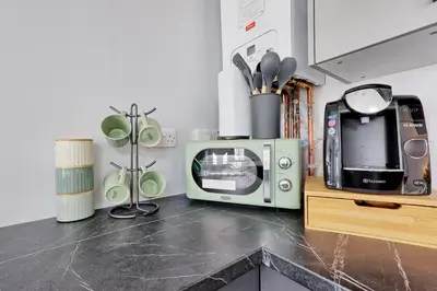 a kitchen with a microwave on a counter with aether at Studio By Homestyles Hosts Short Lets & Serviced Accommodation Widford - Free WiFi in Writtle