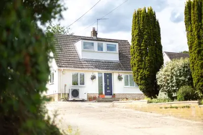 a white house with a blue door and trees at Lazy Acre, Suffolk in Hopton