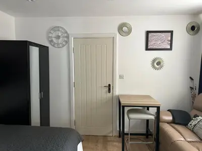 a bedroom with a bed and a table and a door at A Comfortable and Cosy Self Contained Room in Navestock