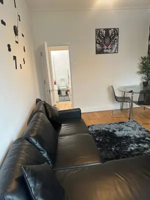 a living room with a leather couch and a table at The Retreat On Retreat Road in Southend-on-Sea
