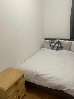 a small bedroom with a bed and a wooden nightstand at The Retreat On Retreat Road in Southend-on-Sea