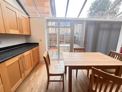 a kitchen with a table and chairs and a large window at 4 Bedroom House Colchester in Colchester