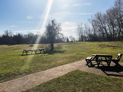 two picnic tables in a field with a rainbow in the sky at Blackberry Barn by The Suffolk Cottage Collection in Long Melford