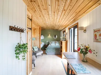 a bedroom with a bed and a table in a room at Luxury Shepherd Hut with Private Hot Tub in Swaffham Bulbeck