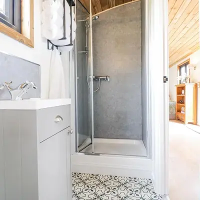 a bathroom with a shower with a glass door at Luxury Shepherd Hut with Private Hot Tub in Swaffham Bulbeck