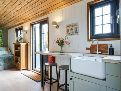 a kitchen with a sink and a counter with stools at Luxury Shepherd Hut with Private Hot Tub in Swaffham Bulbeck