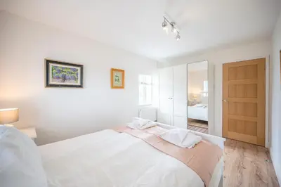 a white bedroom with a large bed and a door at 19BC, Aldeburgh in Aldeburgh
