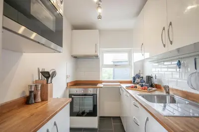 a kitchen with white cabinets and a sink and a window at 19BC, Aldeburgh in Aldeburgh