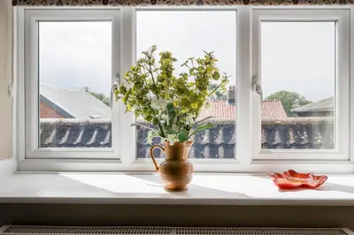 a vase with flowers sitting on a window sill at Market View, Framlingham in Framlingham