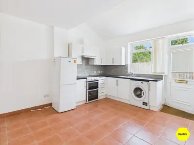 a kitchen with white cabinets and a washer and dryer at New Spacious apartment in Milton