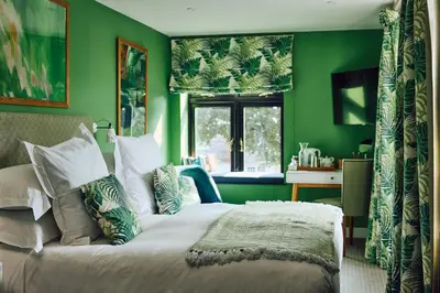 a green bedroom with a bed and a window at The White Hart Inn in West Mersea