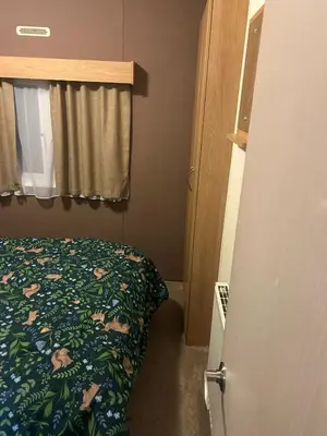 a small bedroom with a bed and a window at 2 bed caravan seawick hoilday Park in Clacton-on-Sea
