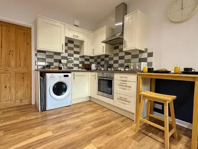 a kitchen with white cabinets and a washer and dryer at 2 bed Elegant Flat in Stansted with parking in Stansted Mountfitchet