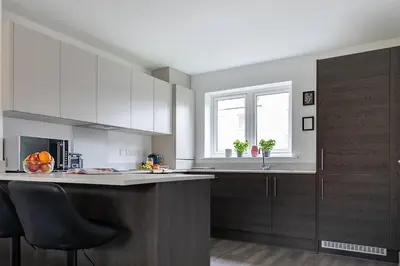 a kitchen with white cabinets and a counter top at Beaulieu Rest 3 Bed House Chelmsford in Broomfield