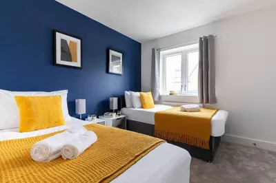 a bedroom with two beds and a blue wall at Beaulieu Rest 3 Bed House Chelmsford in Broomfield