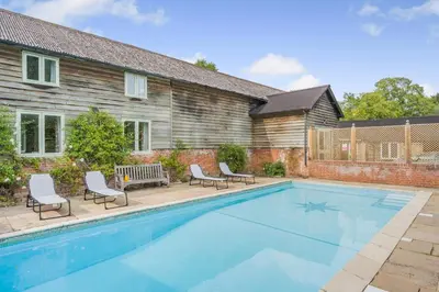 a swimming pool with chairs and a house at 4 Bed in Hartest oc-w32685 in Hartest