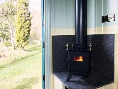 a stove in a room with a window at The Hollies Shepherds Hut by The Suffolk Cottage Collection in Sutton