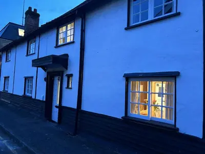 a white house with a lit up window at Memorial University, Harlow Campus in Burnt Mill