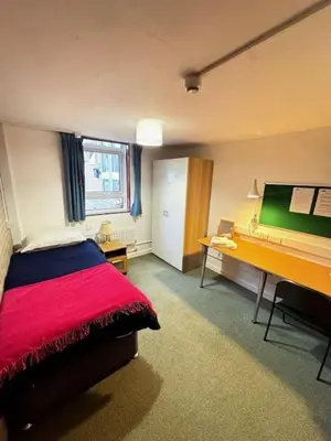 a bedroom with a desk and a bed with a red blanket at Memorial University, Harlow Campus in Burnt Mill