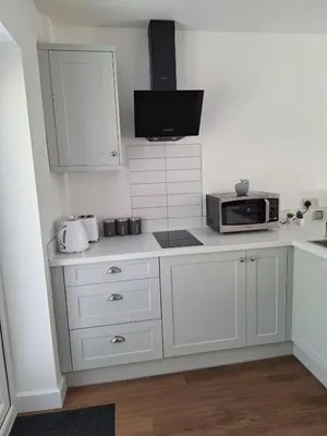 a white kitchen with a microwave and a counter at New Annexe in Gosfied in Gosfield