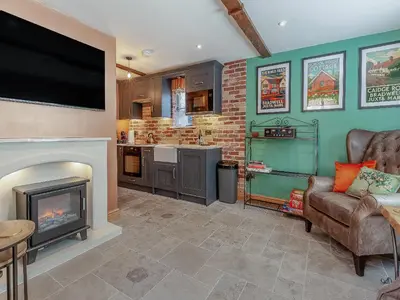 a living room with a fireplace and a flat screen tv at The School House Cottage in Bradwell on Sea