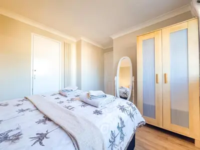 a bedroom with a bed and a mirror at House - sleeps 7 private garden & parking in Basildon