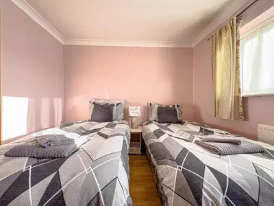 two beds sitting next to each other in a room at House - sleeps 7 private garden & parking in Basildon