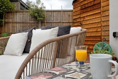 a table with a glass of orange juice on a patio at Beautiful 5 bed house, relaxing garden and driveway parking 10 min to the beach in Southend-on-Sea