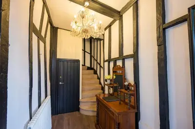 a hallway with a black door and a chandelier at Silk Room, The Merchant House, Ipswich in Ipswich