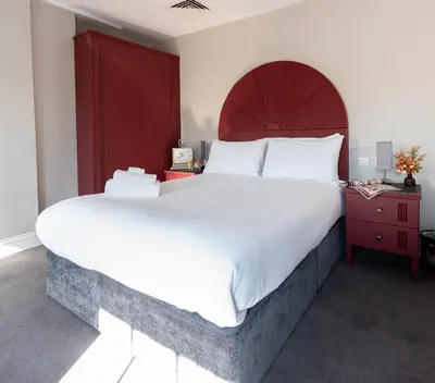 a bedroom with a large bed and a red headboard at Poets 24 in Ely