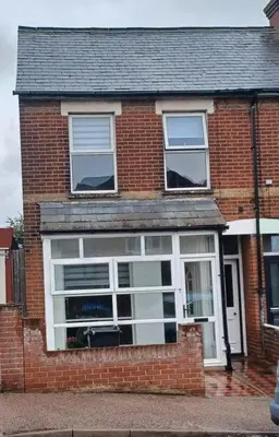 a brick house with a large window on it at Beachside Terrace in Dovercourt