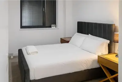 a bedroom with a large bed with a black headboard at Modern 2 Bed Flat with parking Next to Basildon Station in Laindon