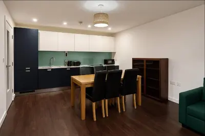 a kitchen with a wooden table and black chairs at Modern 2 Bed Flat with parking Next to Basildon Station in Laindon