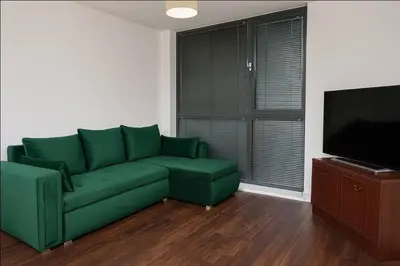 a living room with a green couch and a flat screen tv at Modern 2 Bed Flat with parking Next to Basildon Station in Laindon