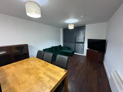 a living room with a table and a green couch at Modern 2 Bed Flat with parking Next to Basildon Station in Laindon