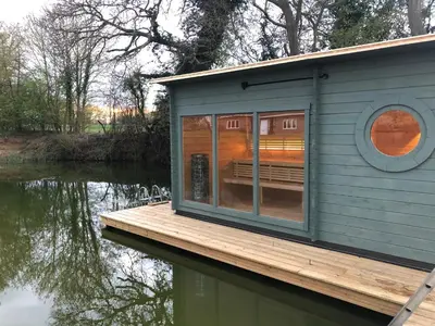 a tiny house on a dock on a body of water at Muntjac Cabin in Elmswell