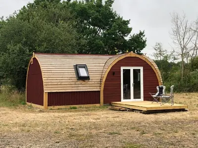 a small shed with a porch and a chair in it at Muntjac Cabin in Elmswell
