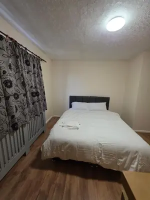 a bedroom with a white bed with a curtain and a table at Spacious Double Room in Basildon Essex in Basildon