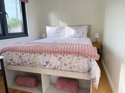 a bedroom with a bed with a pink comforter at The Den in Scoulton