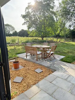 a patio with a table and chairs in a field at The Den in Scoulton