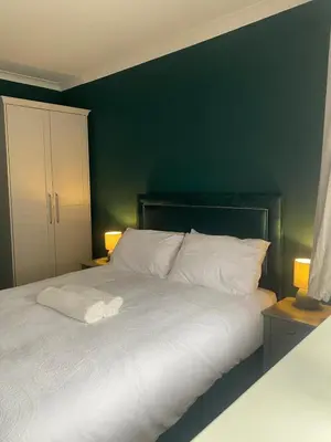 a bedroom with a white bed with a green wall at Two double bedroom self contained Retreat in Thundersley