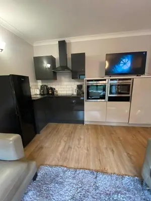 a living room with a large kitchen with black cabinets at Two double bedroom self contained Retreat in Thundersley
