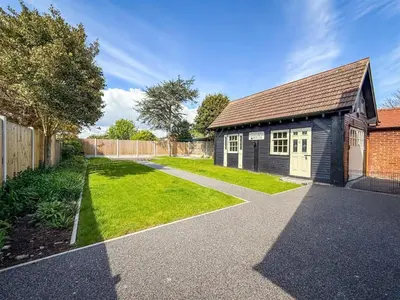 a small house with a driveway next to a yard at Oceanfront 4BR Beach Retreat in Holland-on-Sea