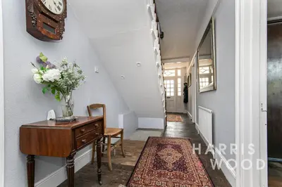 a hallway with a desk and a clock on a wall at Beaulieu in East Bergholt