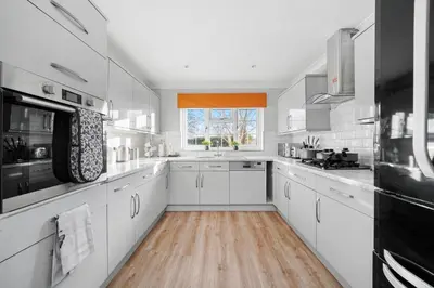 a large kitchen with white cabinets and a window at Detached 6 Bedroom Cambridgeshire Abode - Pets in Whittlesford