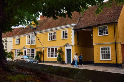 two people standing outside of a yellow house at The Sun Inn in Dedham